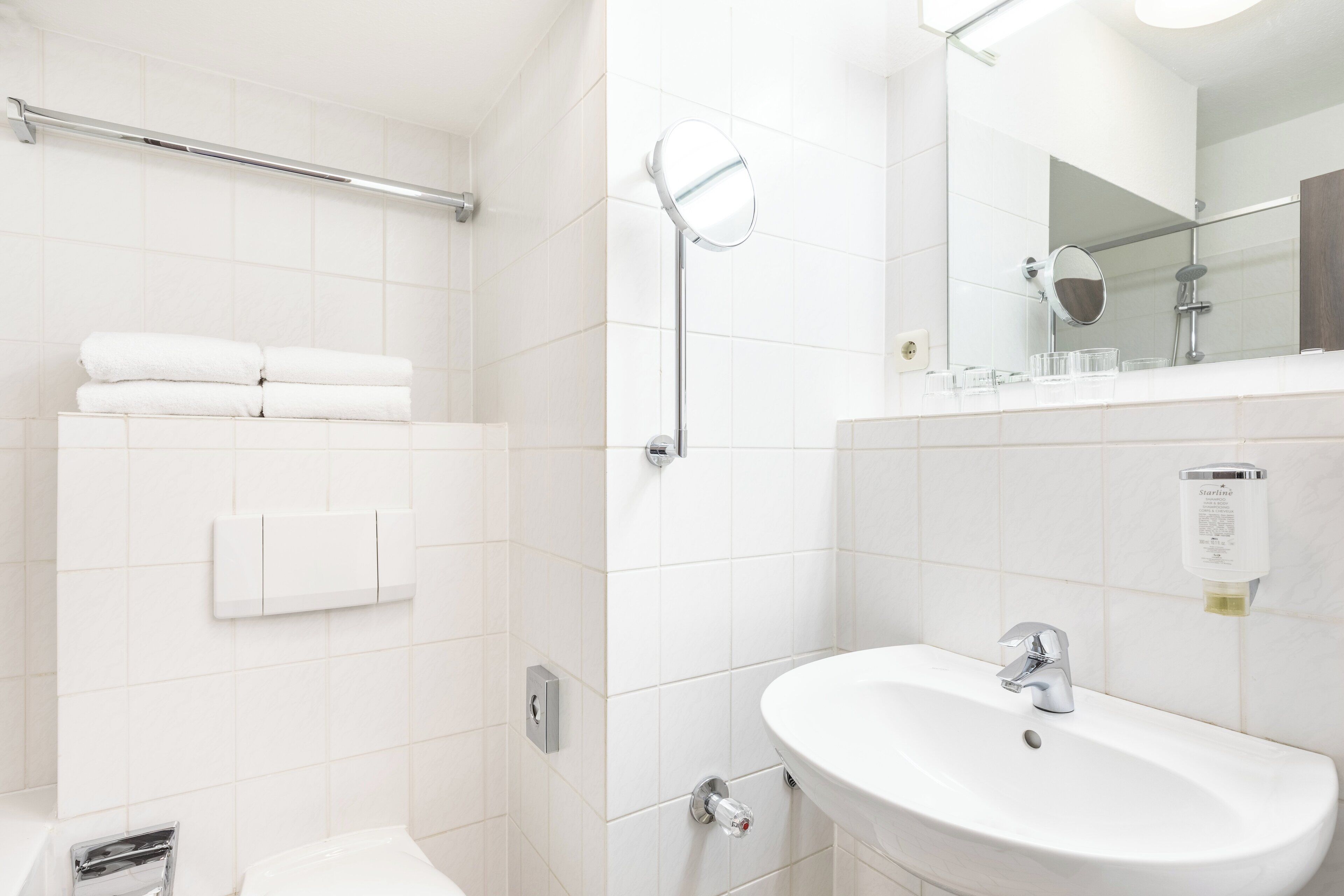 Un baño moderno con un lavamanos blanco, un espejo y un perchero para toallas.