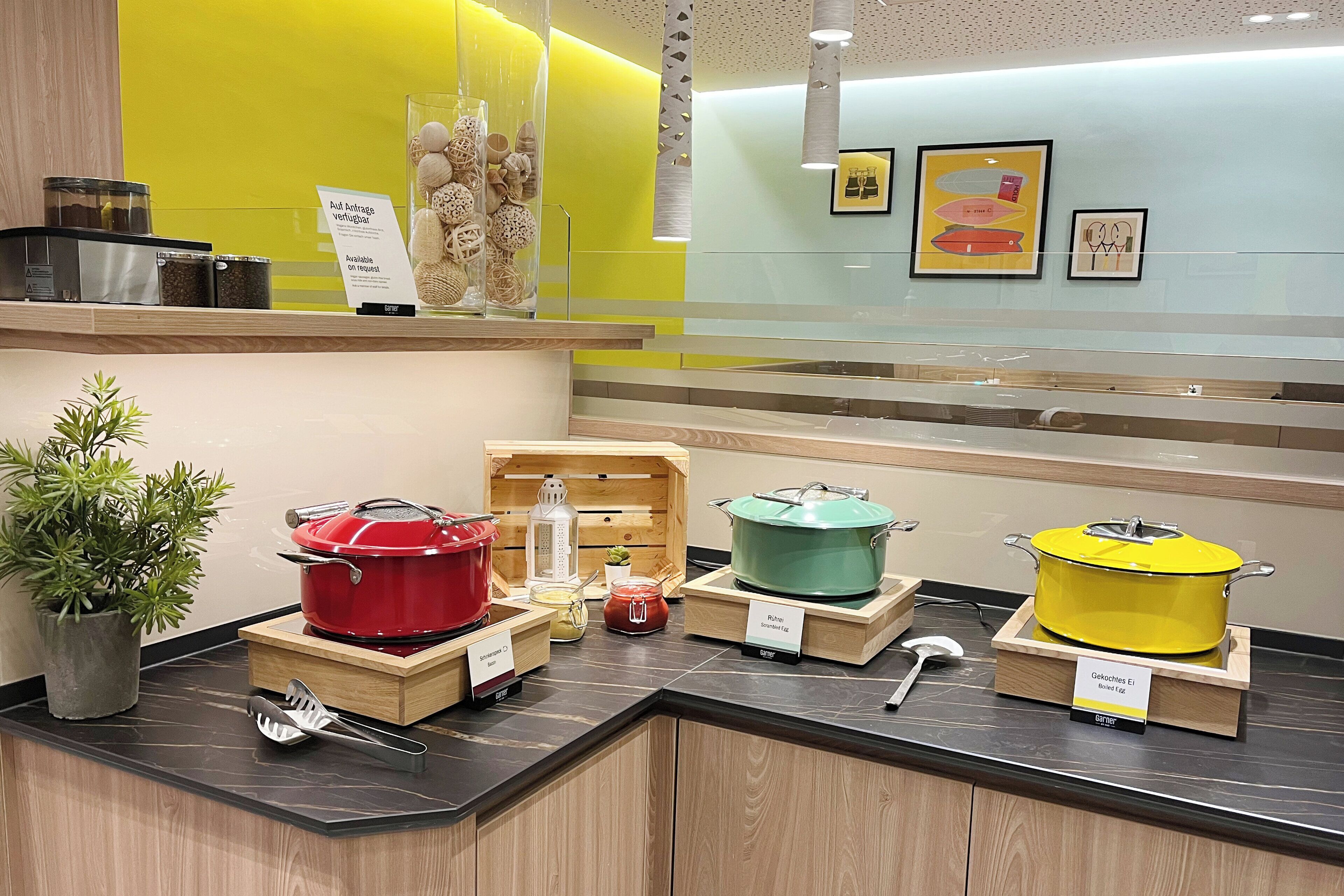 Una encimera de cocina con varias ollas y utensilios, una planta en maceta y un cartel que indica los servicios disponibles.