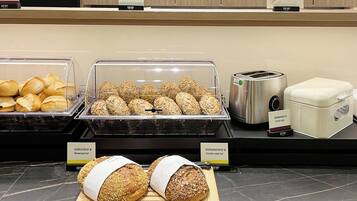 A bakery display with various types of bread and a toaster.