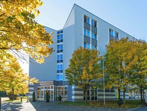 A modern hotel building with a glass facade, a visible entrance, and a parking area with trees. - Hotel Bochum Wattenscheid Affiliated by Meliá (Bochum)