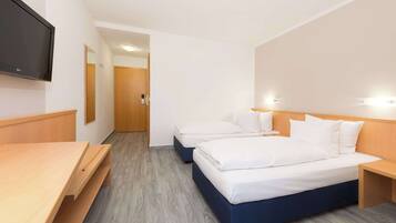 A hotel room with two beds, a wooden desk, a flat-screen TV, and a wooden door.