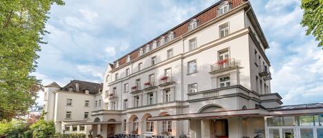 A multi-story hotel with a central courtyard, featuring a covered entrance, outdoor seating, and a bike parking area.