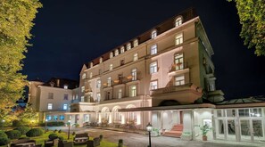 A multi-story hotel with a central courtyard, outdoor seating, and a swimming pool.