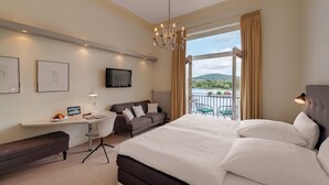 Una habitación de hotel con una cama grande, un escritorio con computadora, un televisor y un balcón con vista al paisaje.