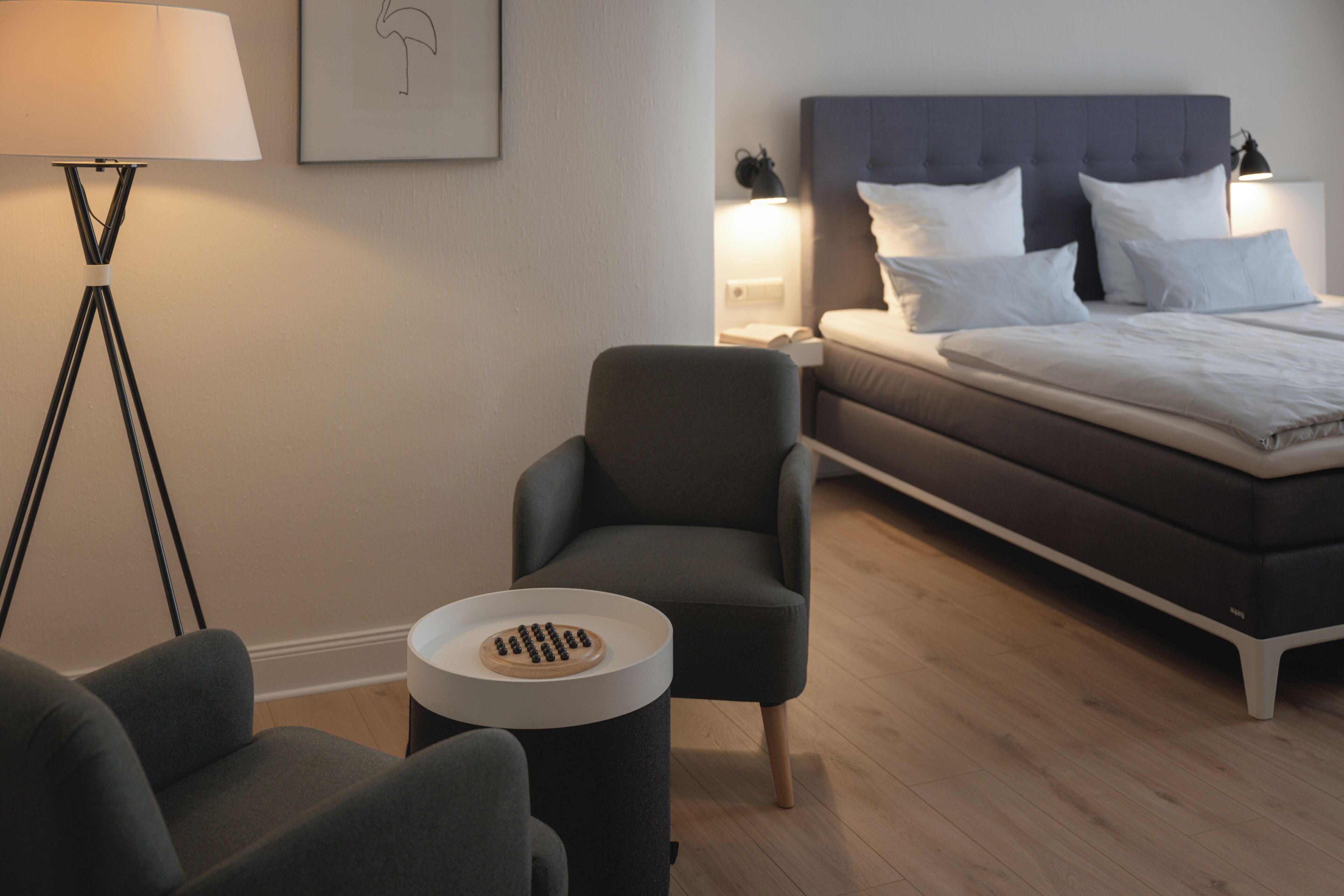 Un dormitorio moderno con cama, mesitas de noche, lámpara y una silla.