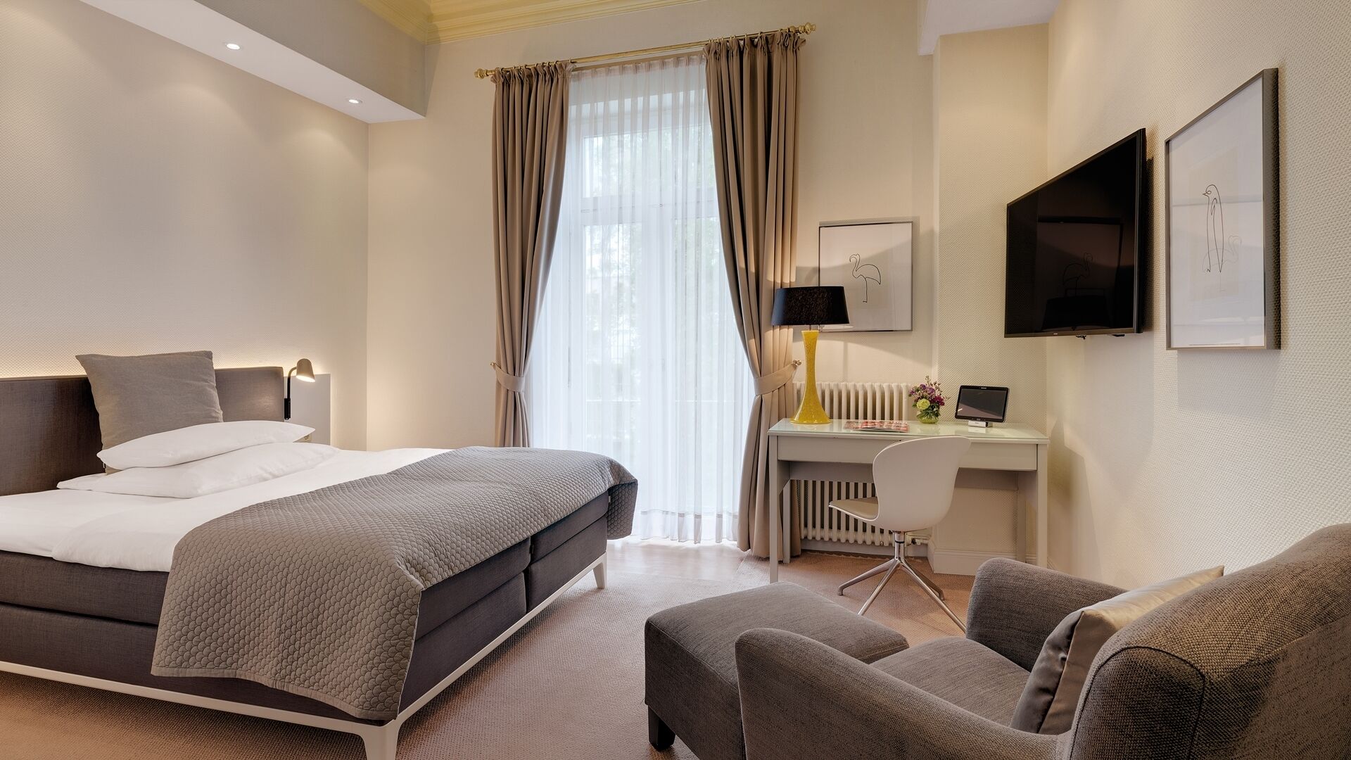 Una habitación de hotel moderna con cama, escritorio, silla y obras de arte.