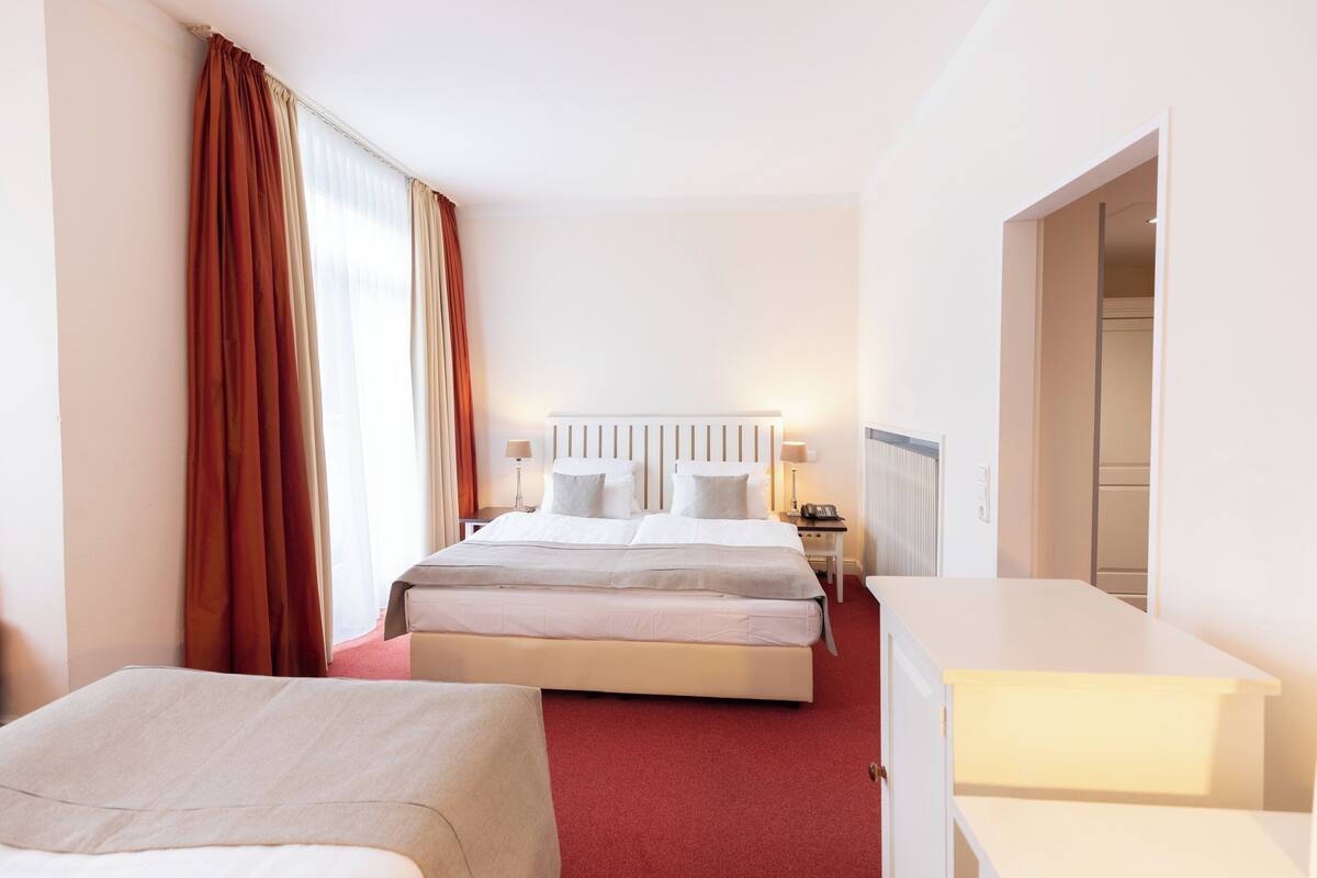 A hotel room with a large bed, a smaller bed, a desk, and a walk-in closet.