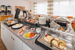 A buffet setup with various food items and a coffee station.