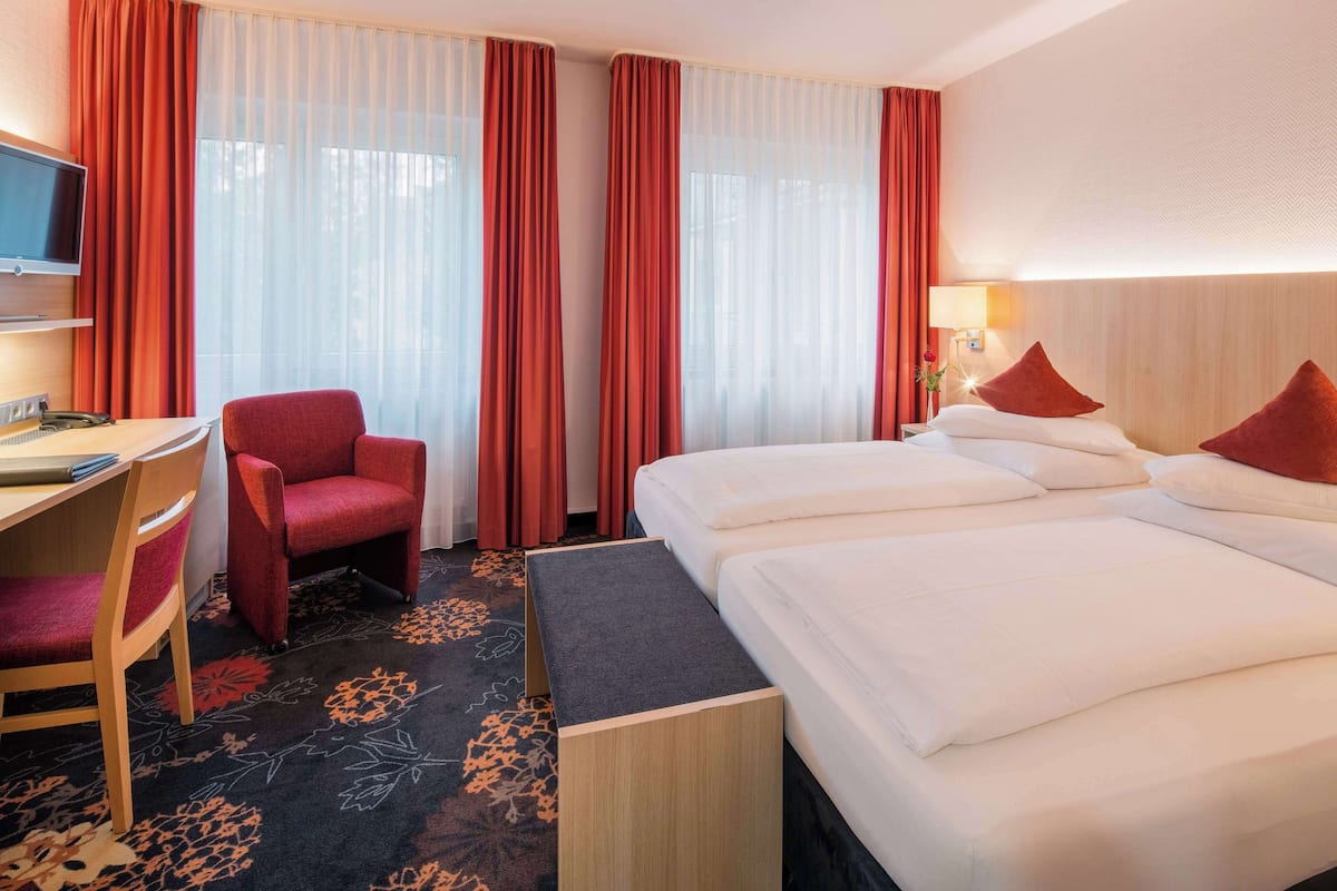 Une chambre d’hôtel avec un lit, un bureau, une chaise et un téléviseur.