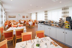 A dining area with multiple tables and chairs, a buffet counter with various food items, and a clean, modern interior design.