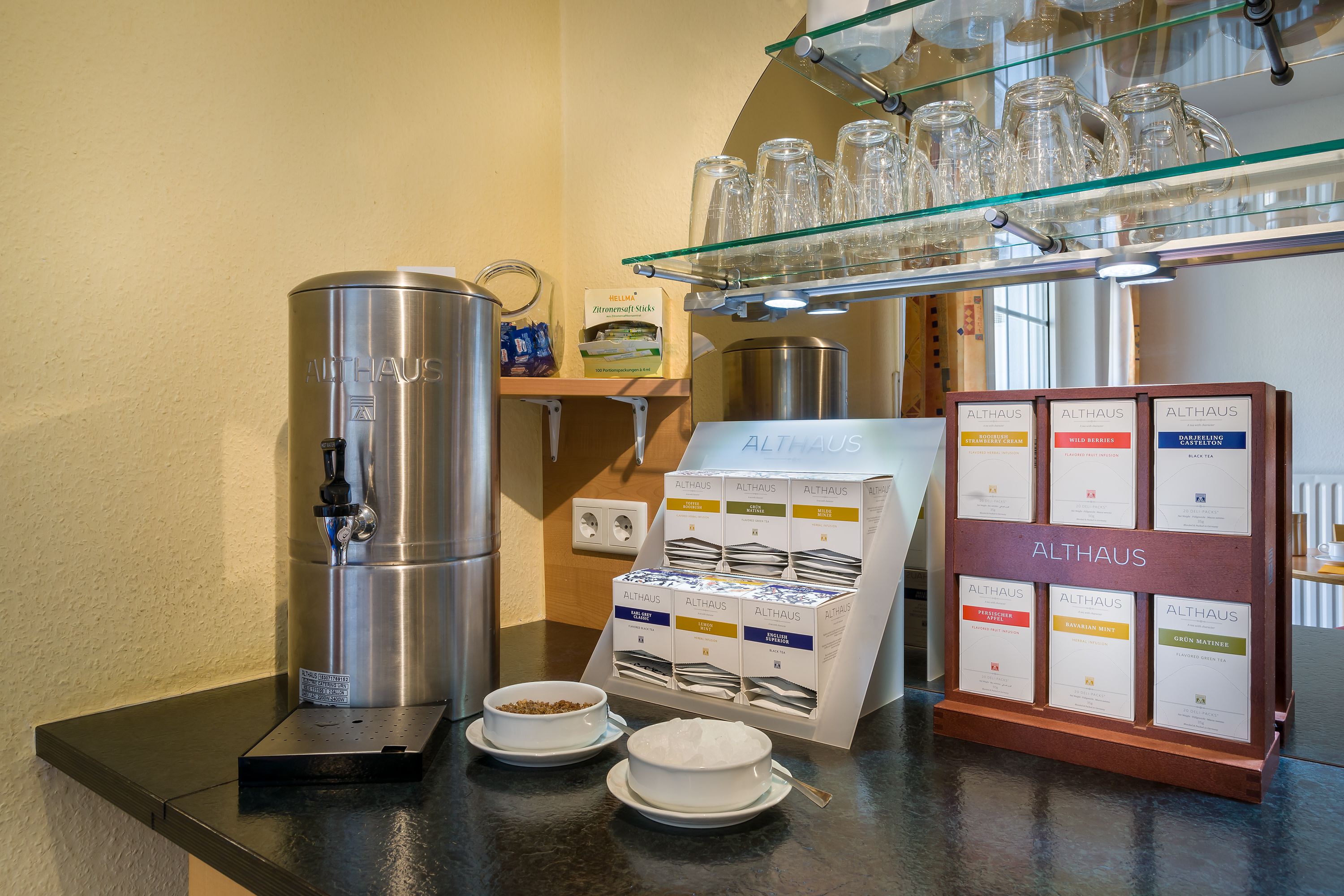 A coffee station with a coffee machine, coffee cups, and a display of coffee boxes.
