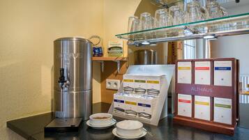 A coffee station with a coffee machine, coffee cups, and a display of coffee boxes.