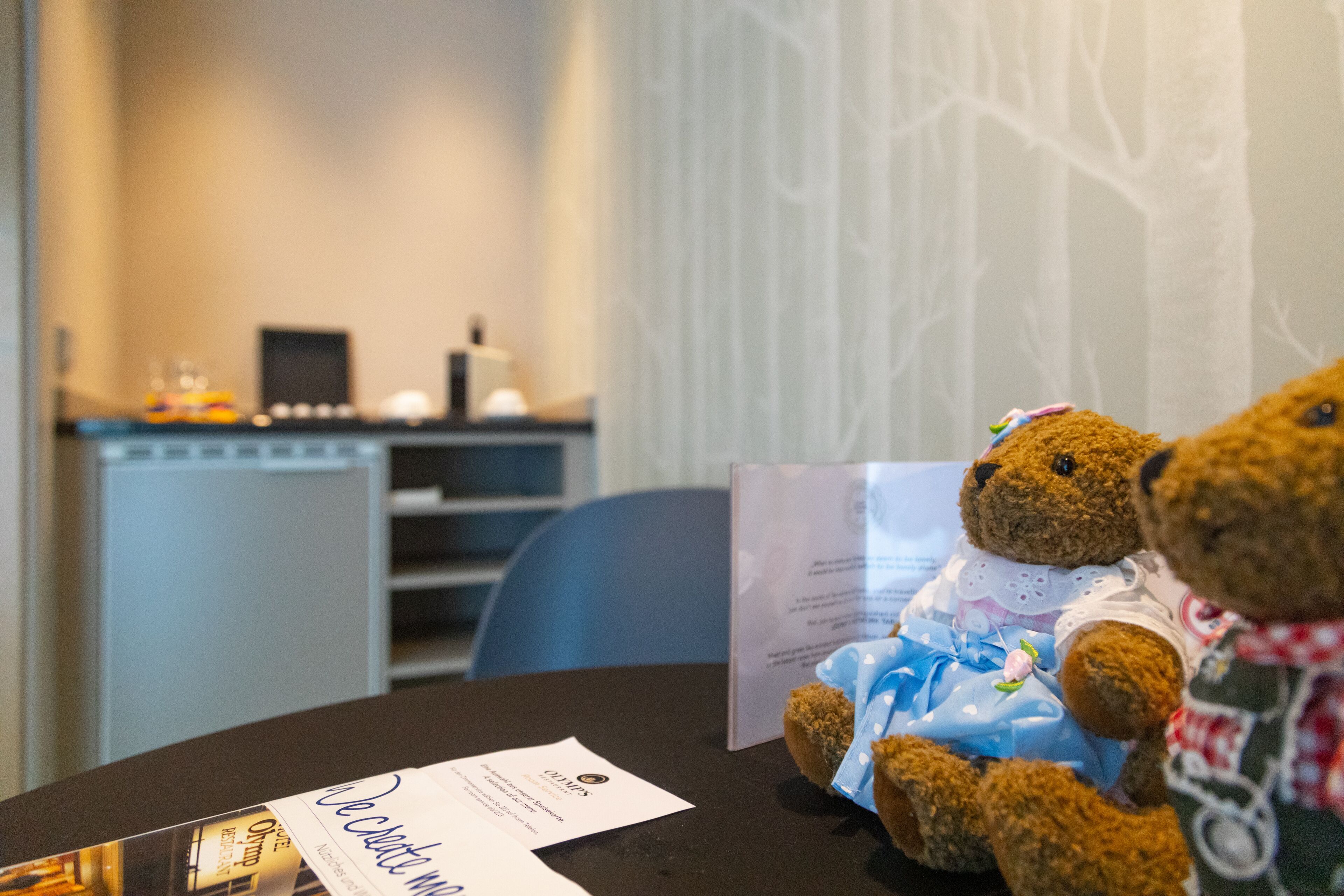 A room with a table, a teddy bear, and a menu.