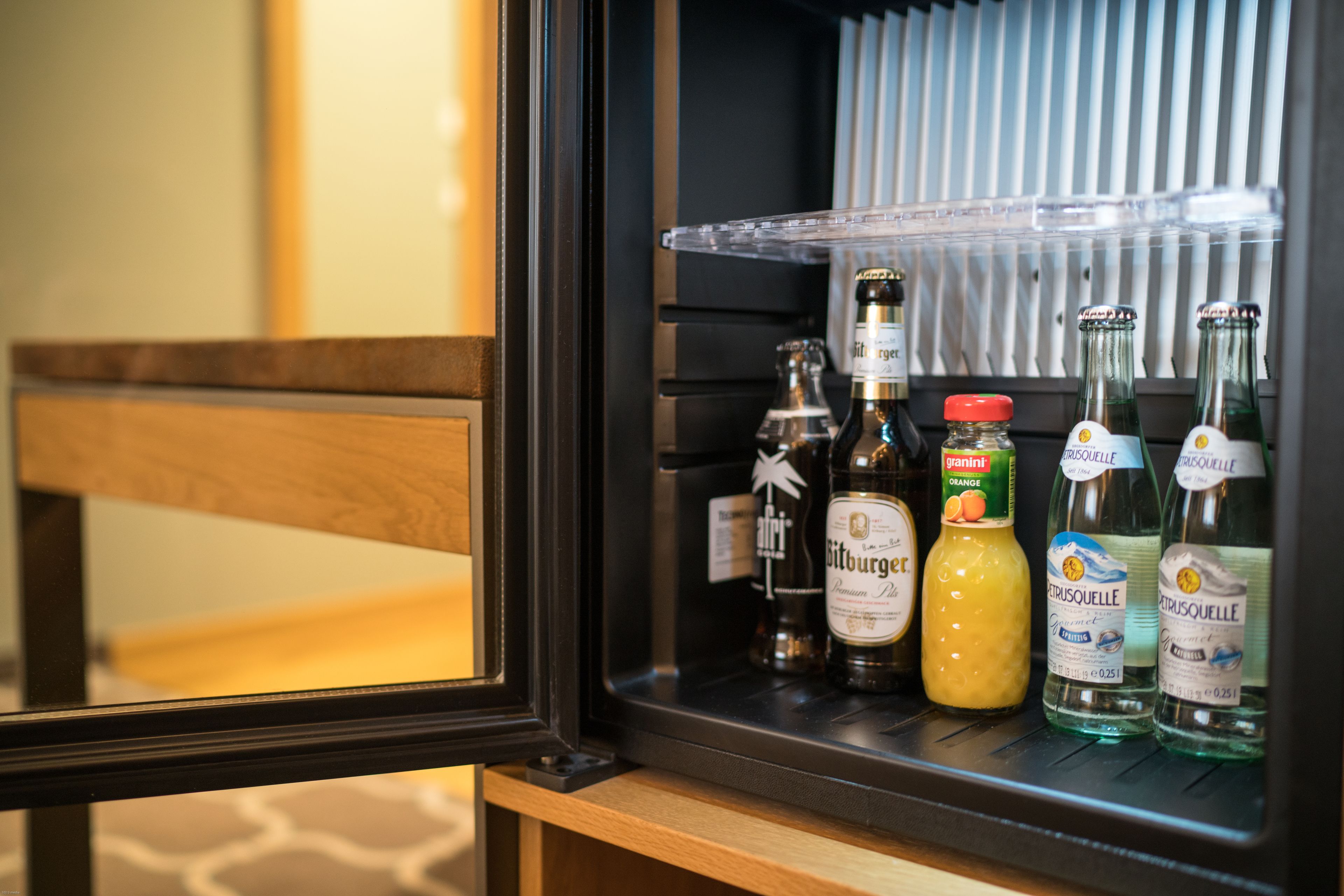 A minibar with various bottles of alcohol, including a bottle of Citrauselle and a bottle of orange juice.