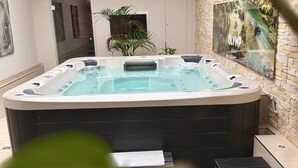 Een bubbelbad in een moderne badkamer met een stenen muur en een schilderij.