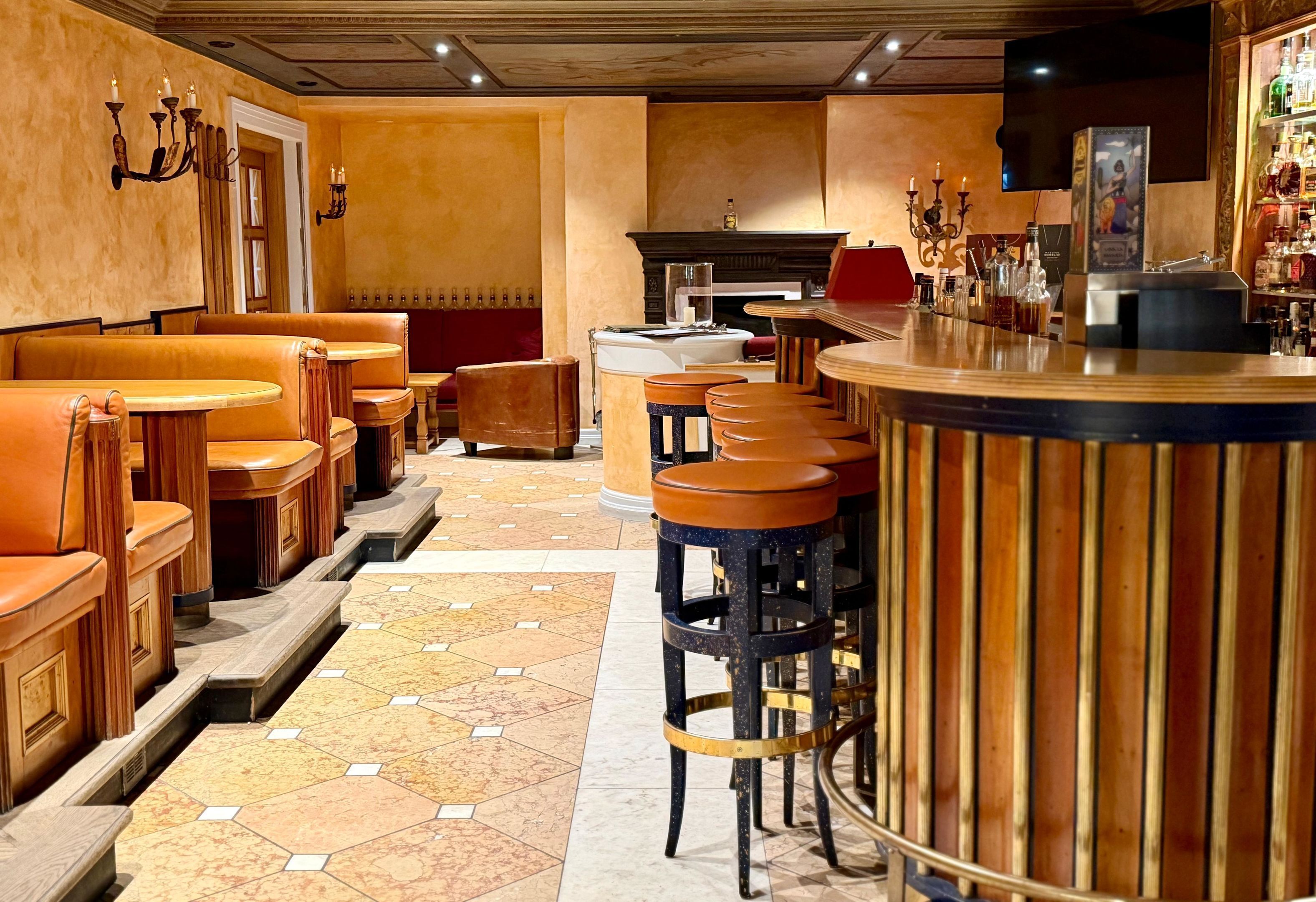A bar area with wooden bar stools, a counter, and a tiled floor.