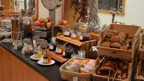 Een buffet met diverse gerechten, waaronder fruit, gebak en sauzen.