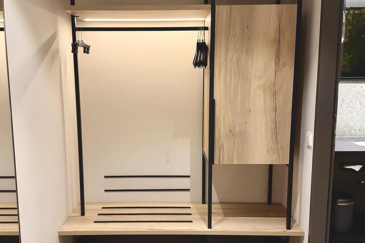 A room with a wooden cabinet, a black metal pole, and a white door.