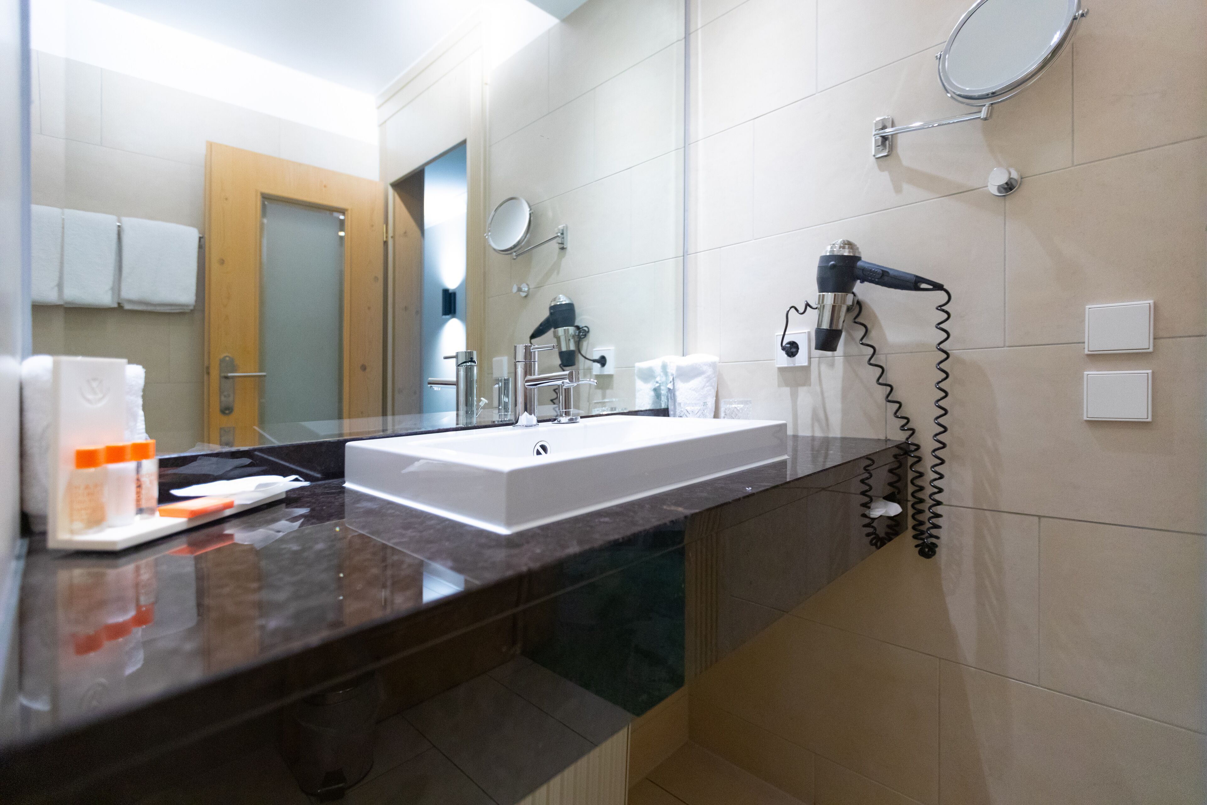 A modern bathroom with a large sink, a hairdryer, and a mirror.