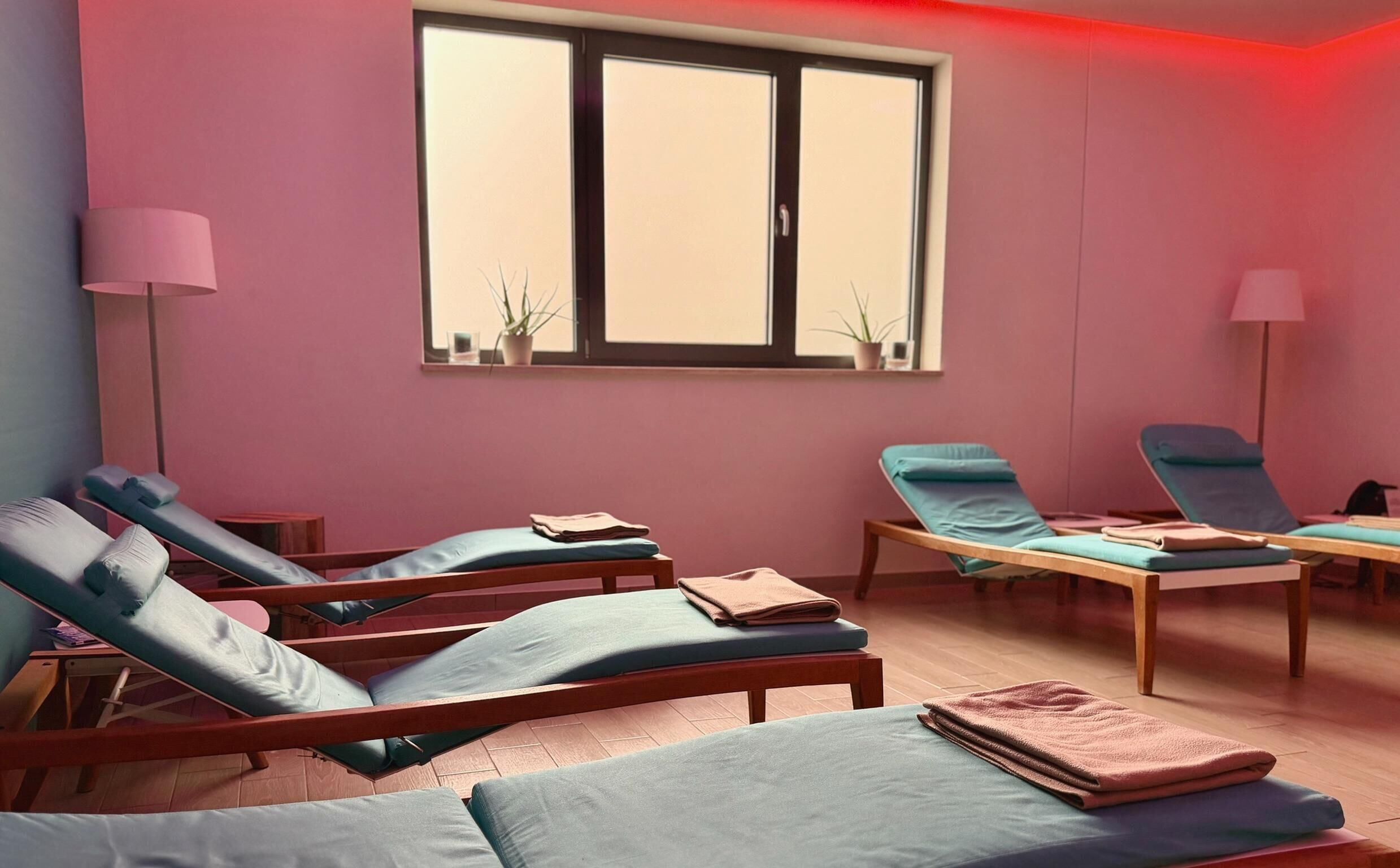 Una habitación con cuatro sillones reclinables, un ventanal y dos lámparas de pie.