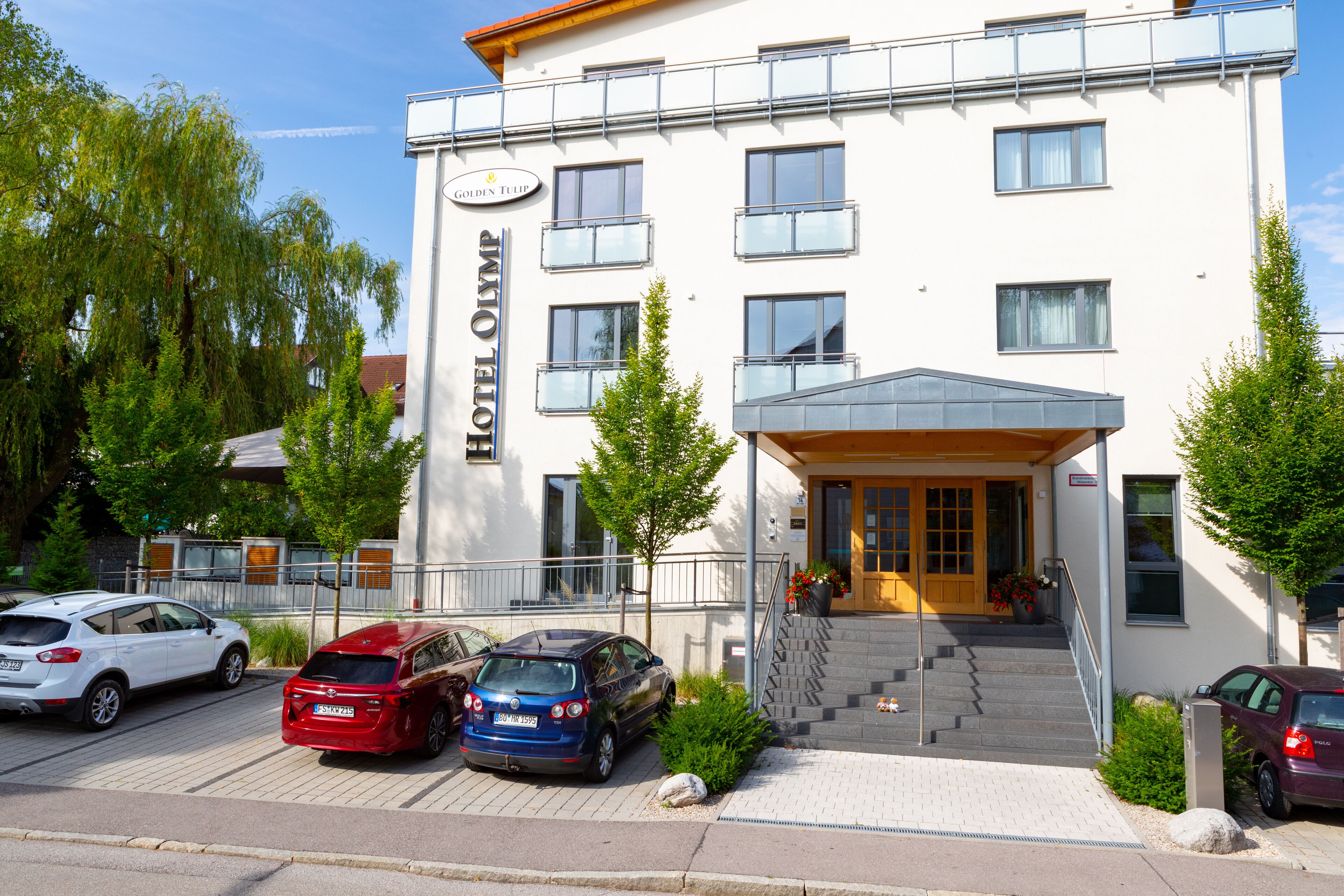A hotel with a white facade, multiple balconies, and a covered entrance.