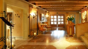 Een hotel lobby met een houten plafond, een receptiebalie, een zithoek met stoelen, en een groot raam met uitzicht.
