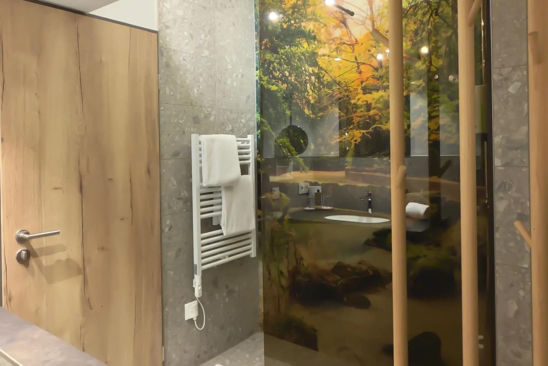 Une salle de bain avec une porte en bois, un porte-serviettes, une cabine de douche en verre et un lavabo.