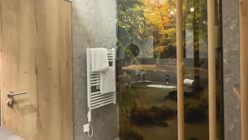 Une salle de bain avec une porte en bois, un porte-serviettes, une cabine de douche en verre et un lavabo.
