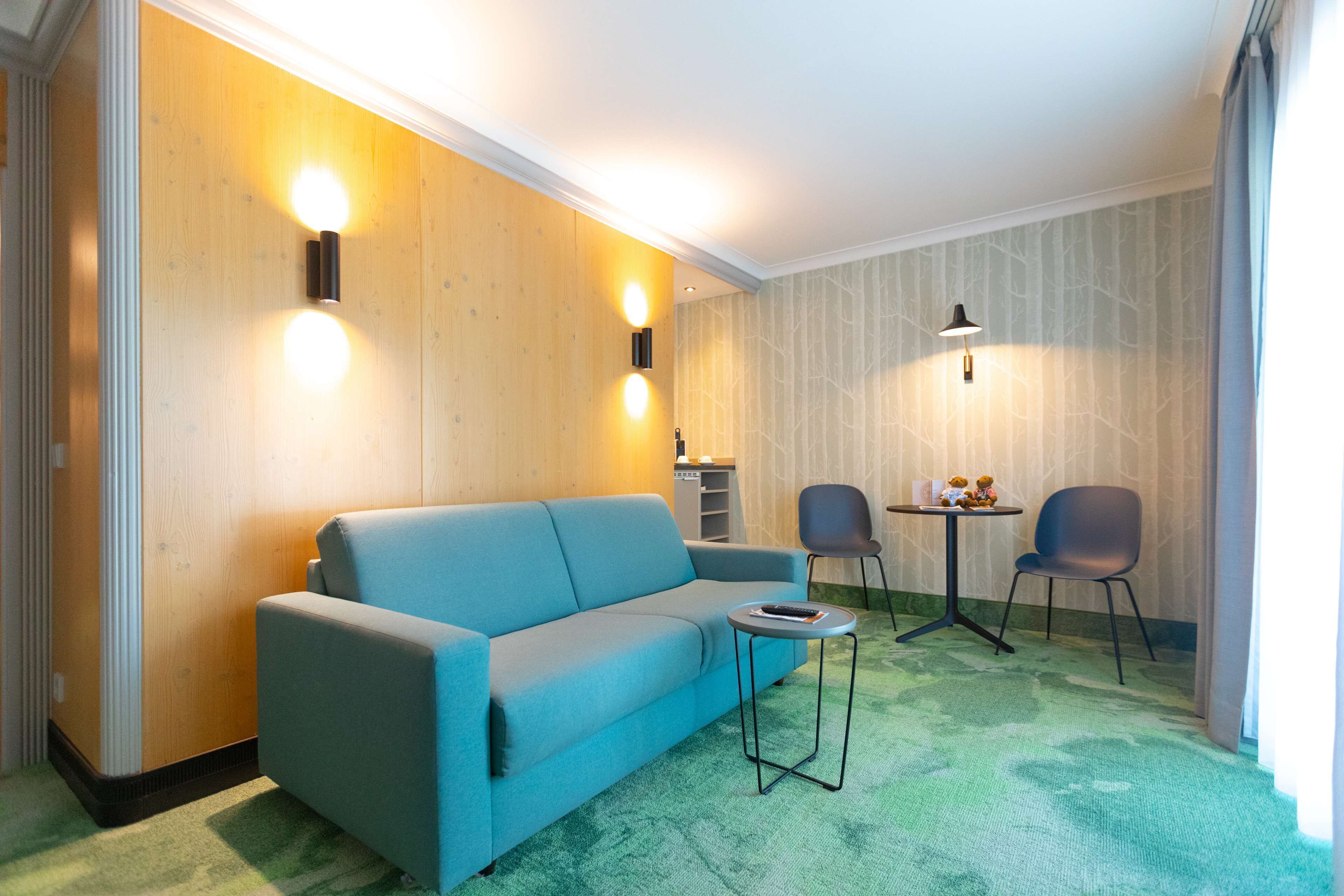 A modern room with a blue sofa, two chairs, a small table, and a lamp.
