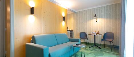 A modern room with a blue sofa, two chairs, a small table, and a lamp.