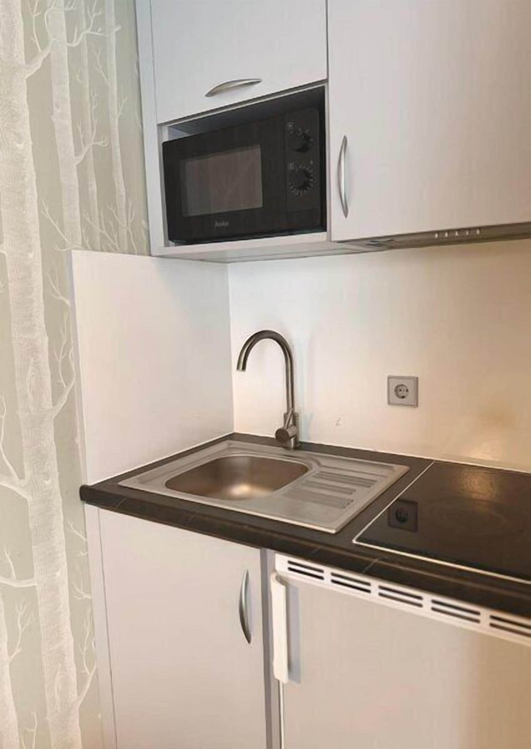 A compact kitchen with a built-in microwave, a sink, and a refrigerator.
