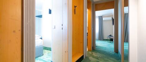 Un pasillo de hotel con paredes de madera, una alfombra verde y un baño visible con ducha e inodoro.
