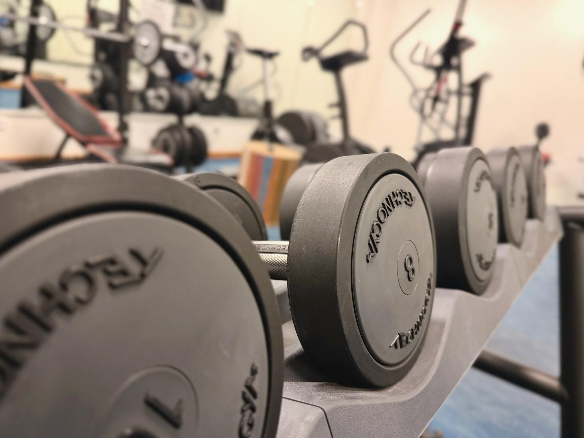 A row of weight plates on a rack in a gym.