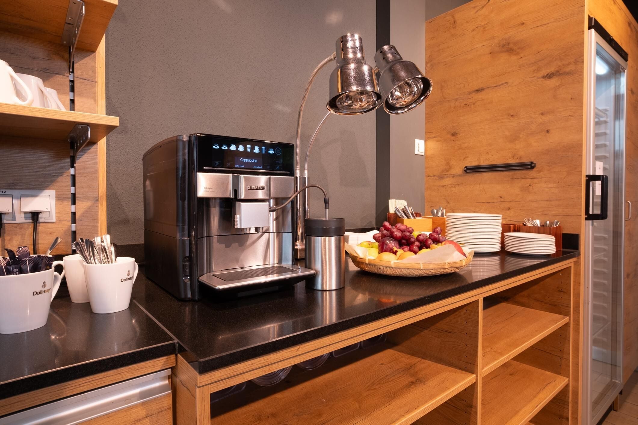 A modern kitchen with a coffee machine, a fruit basket, and a coffee station.