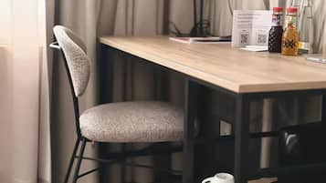Una silla con asiento y respaldo acolchados, una mesa de madera con un código QR y dos botellas sobre la mesa.