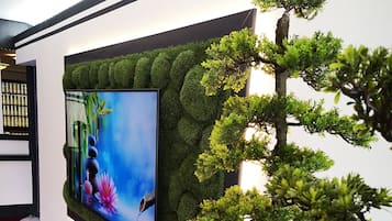 Un intérieur moderne avec un grand téléviseur à écran plat fixé au mur, lequel est recouvert d’une texture verte rappelant de la mousse.