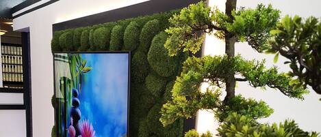 Un interior moderno con un televisor de pantalla plana grande montado en una pared con textura similar al musgo verde.