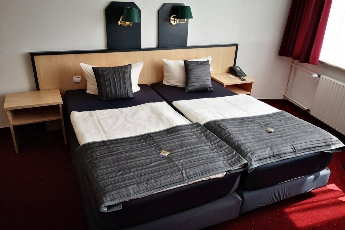 Un lit double avec deux oreillers, une table de chevet, une lampe et un téléphone.