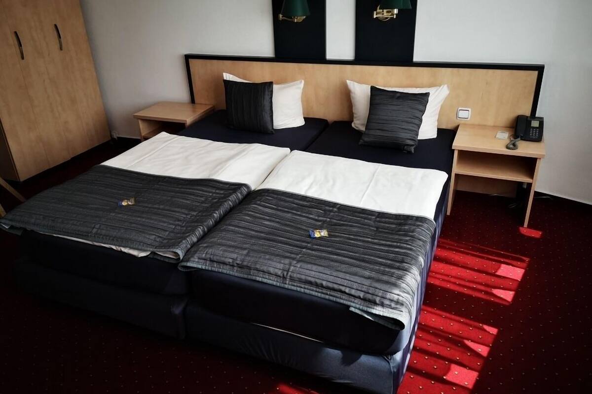 Une chambre d’hôtel avec un lit double, deux tables de chevet, une petite table et un bureau avec un téléphone.