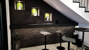 Una cocina moderna con salpicadero de piedra oscura, dos taburetes de bar y una pequeña mesa redonda.