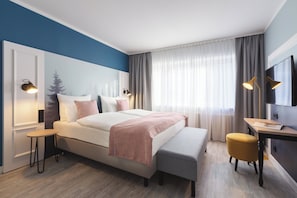 Una habitació d'hotel moderna amb un llit gran, taules de nit, escriptori i televisió.