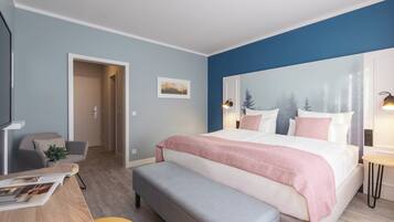 A modern bedroom with a large bed, a desk with a chair, a bench, and a wall-mounted lamp.