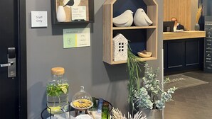 Una zona de recepción con un cartel de 'Solo personal', un estante con forma de casa de madera con adornos, un dispensador de agua con botella de vidrio y un letrero que dice 'Cosas buenas para que las tengas'.
