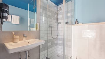 A modern bathroom with a glass-enclosed shower, a sink, and a mirror.