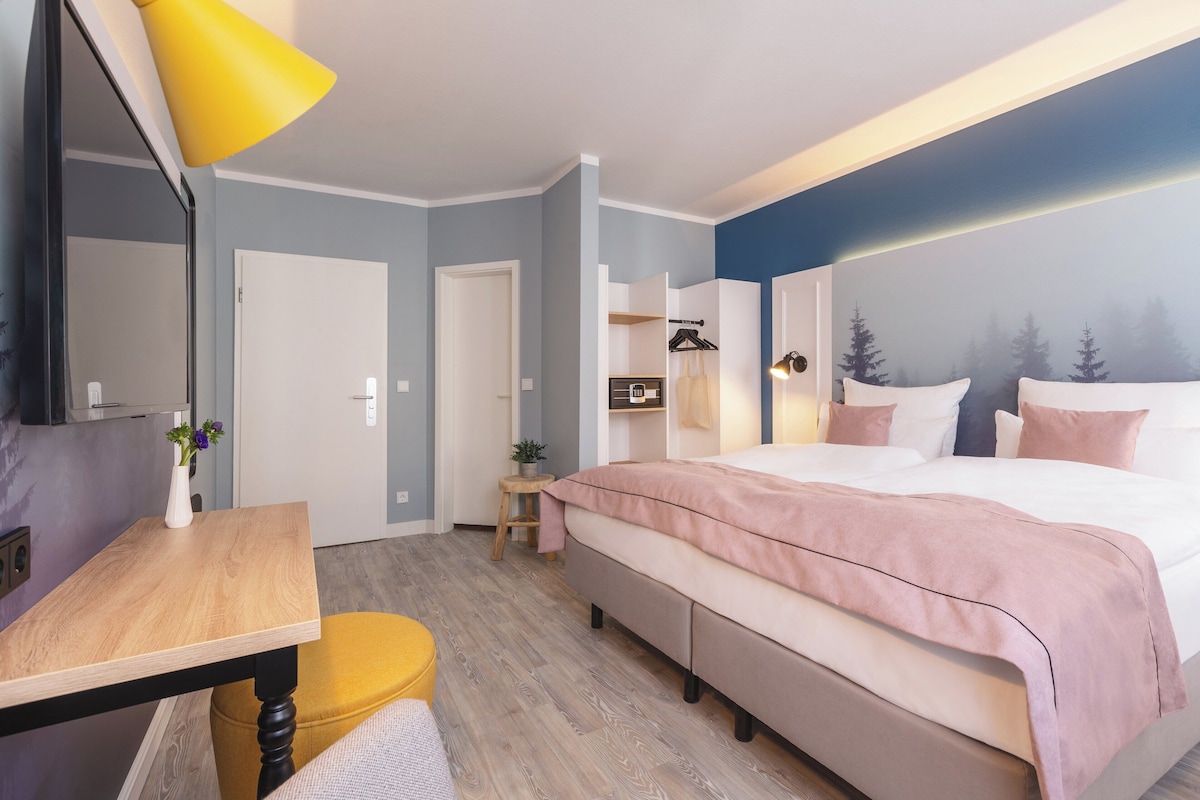 Um quarto moderno com uma cama, mesas de cabeceira, escrivaninha e uma cadeira.