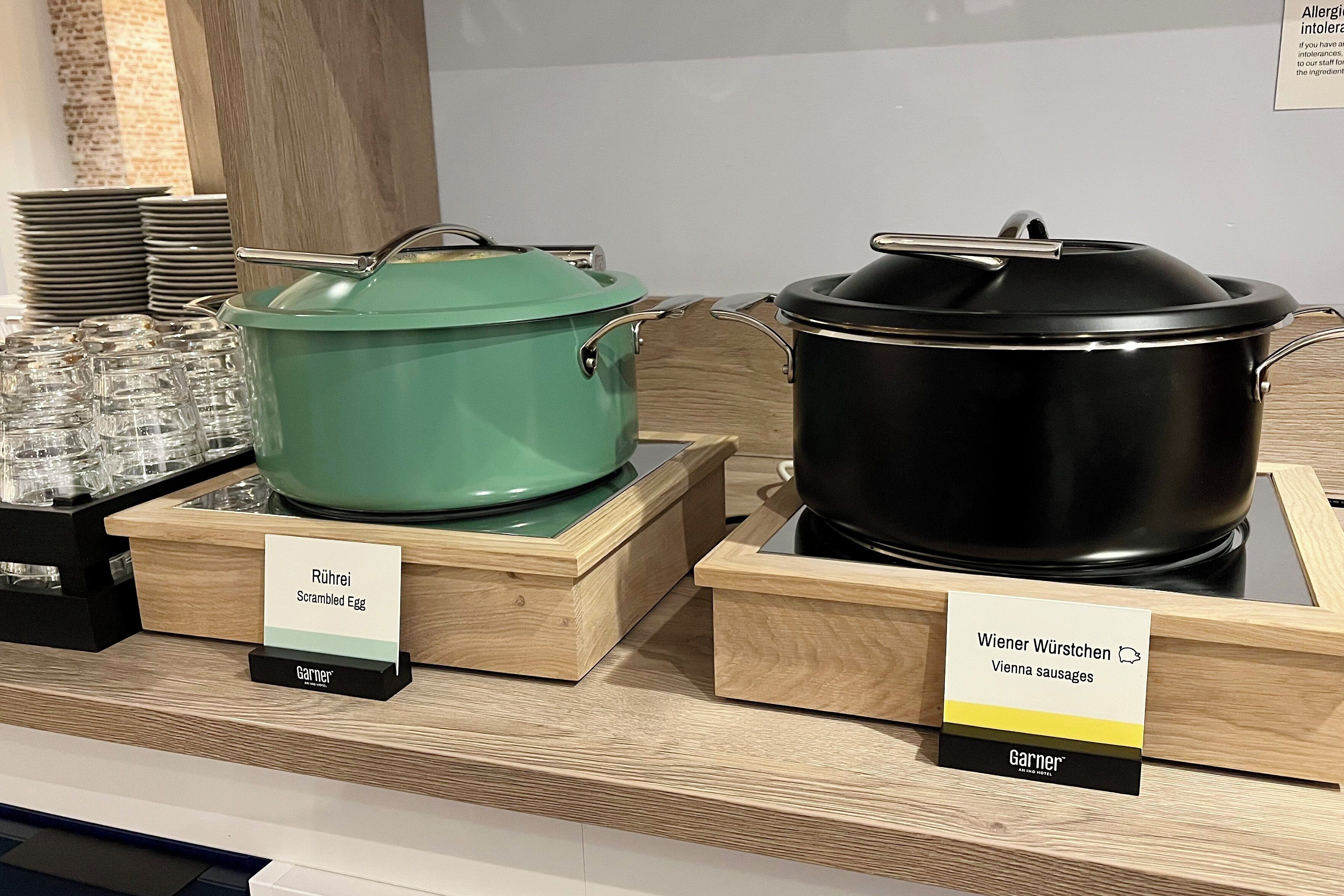 Two cooking pots on display with labels indicating they are for scrambled eggs and Vienna sausages.
