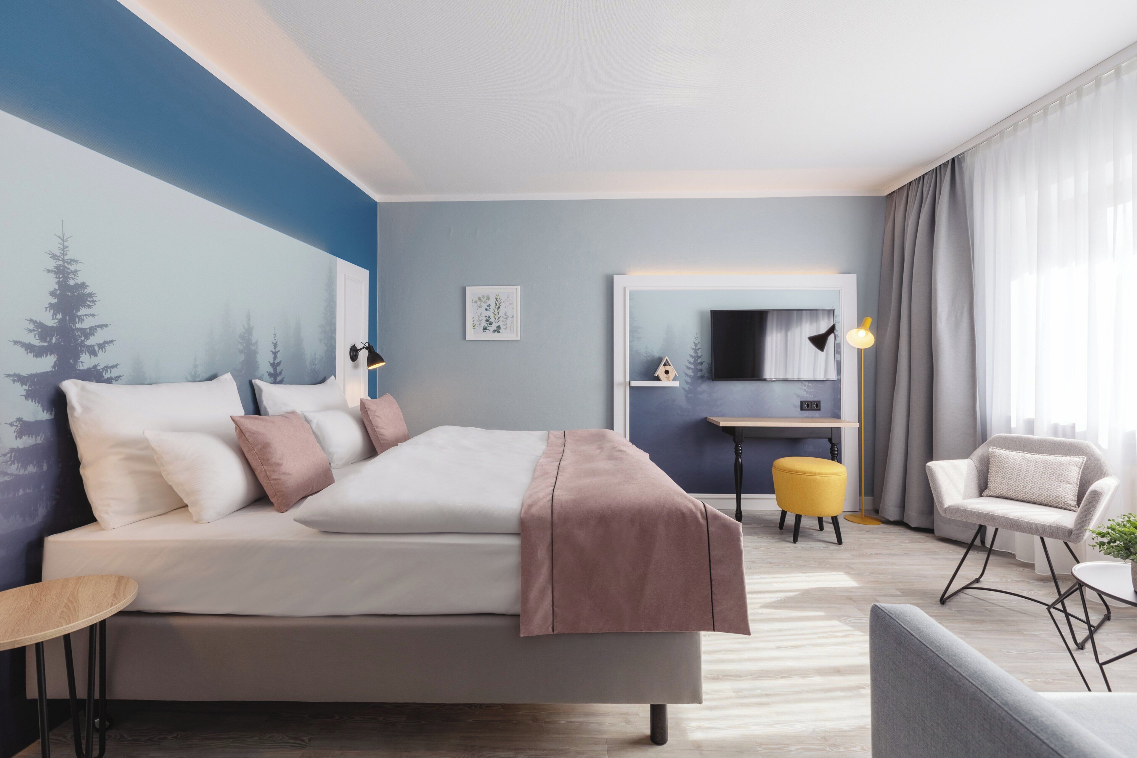 Ett modernt hotellrum med en stor säng, ett skrivbord och en stol.
