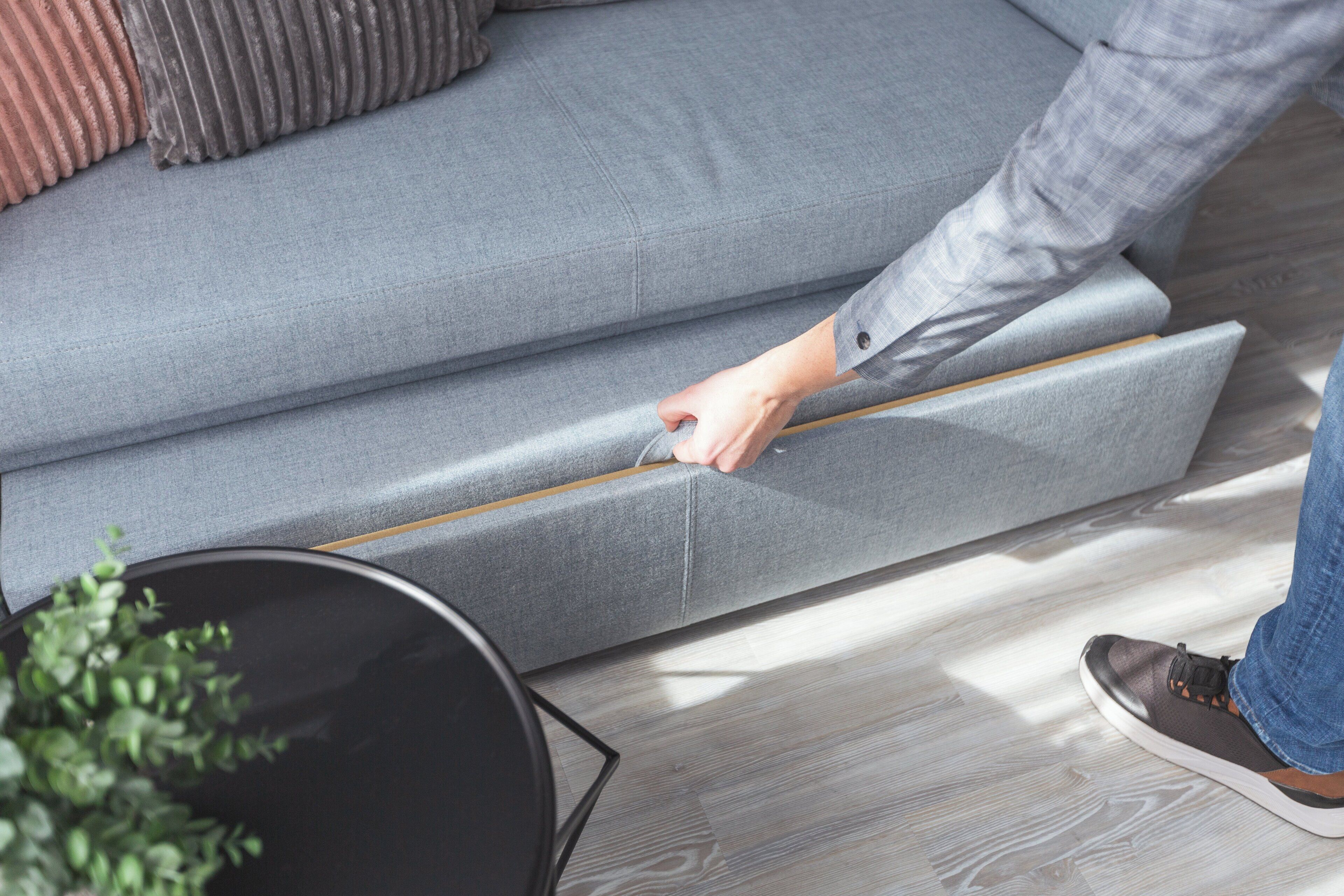 A person adjusting a sofa's reclining mechanism.