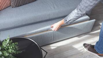 A person adjusting a sofa's reclining mechanism.