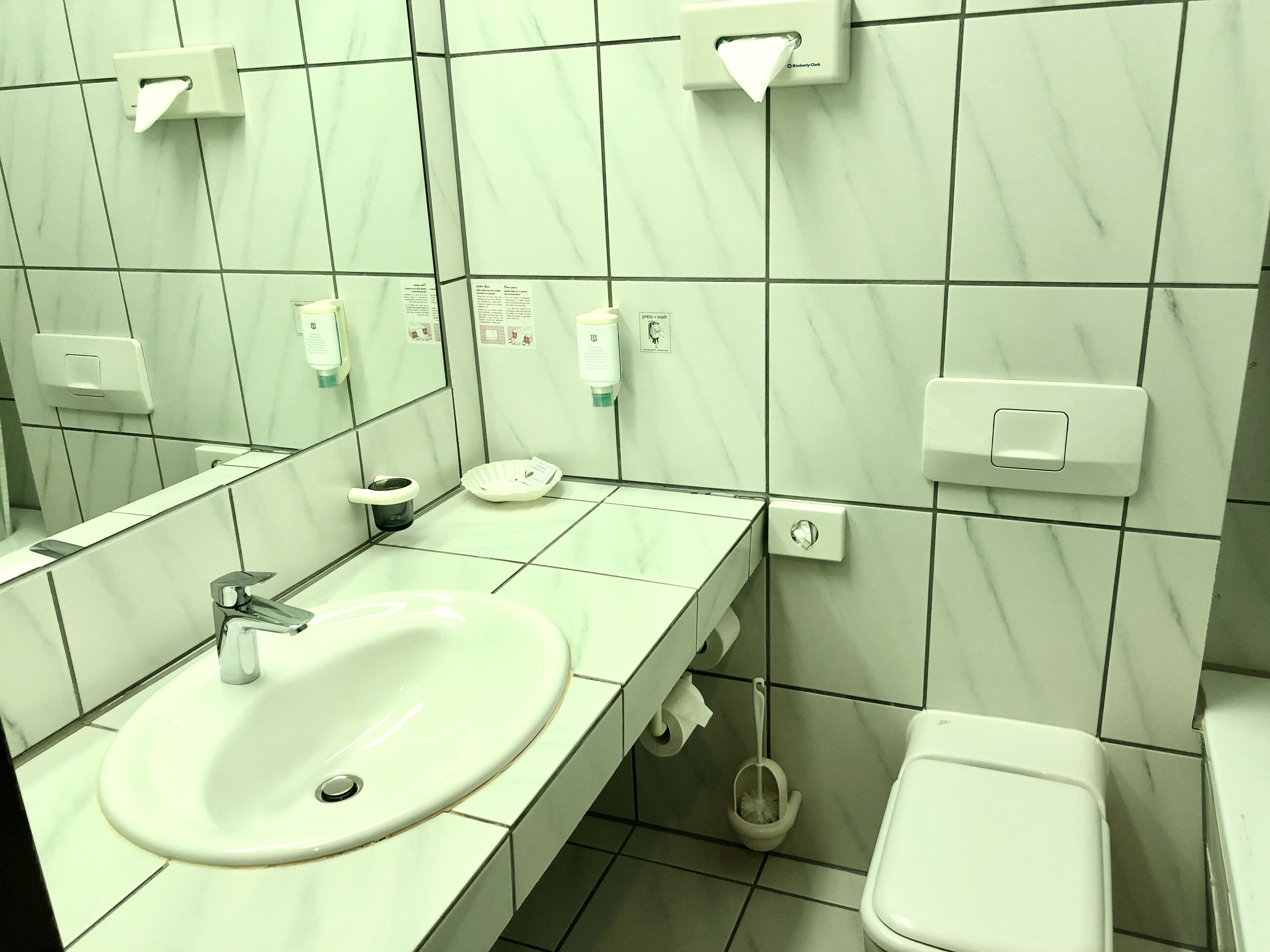 Ein Badezimmer mit Waschbecken, Toilette und Handtrockner.